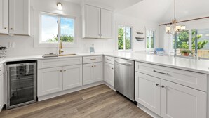 Una cocina moderna con armarios blancos, lavavajillas de acero inoxidable y piso de madera.