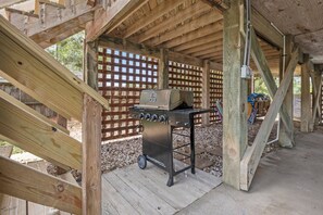 Ein Grill unter einer hölzernen Überdachung, im Hintergrund ein Lattenzaun.