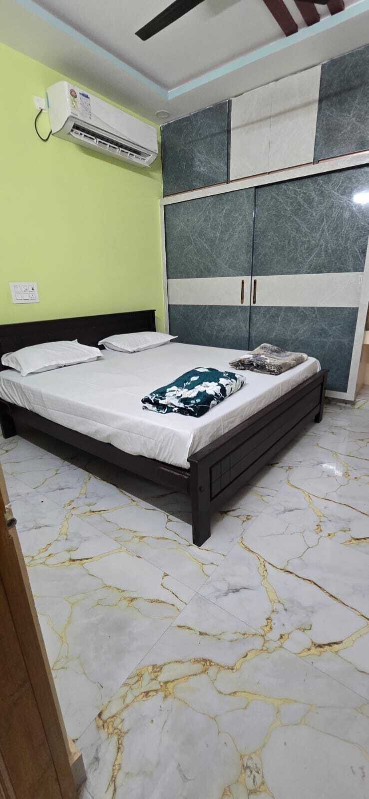 A bedroom with a bed, wardrobe, and an air conditioning unit.