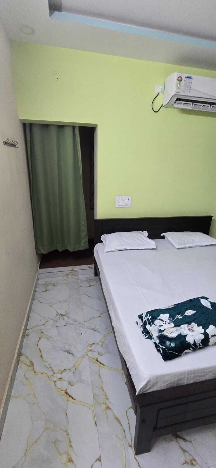 Ein Schlafzimmer mit einem Bett, einem grünen Vorhang, einer Klimaanlage und einem fußbodenähnlichen Marmorbelag.