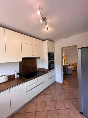 A modern kitchen with white cabinets, a black stove, and a built-in oven. - Near Saint Tropez Charming 4 bedroom house swimming pool garden  with AC (La Croix-Valmer)
