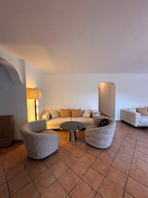 Een woonkamer met een bank, twee fauteuils, een salontafel en een lamp.