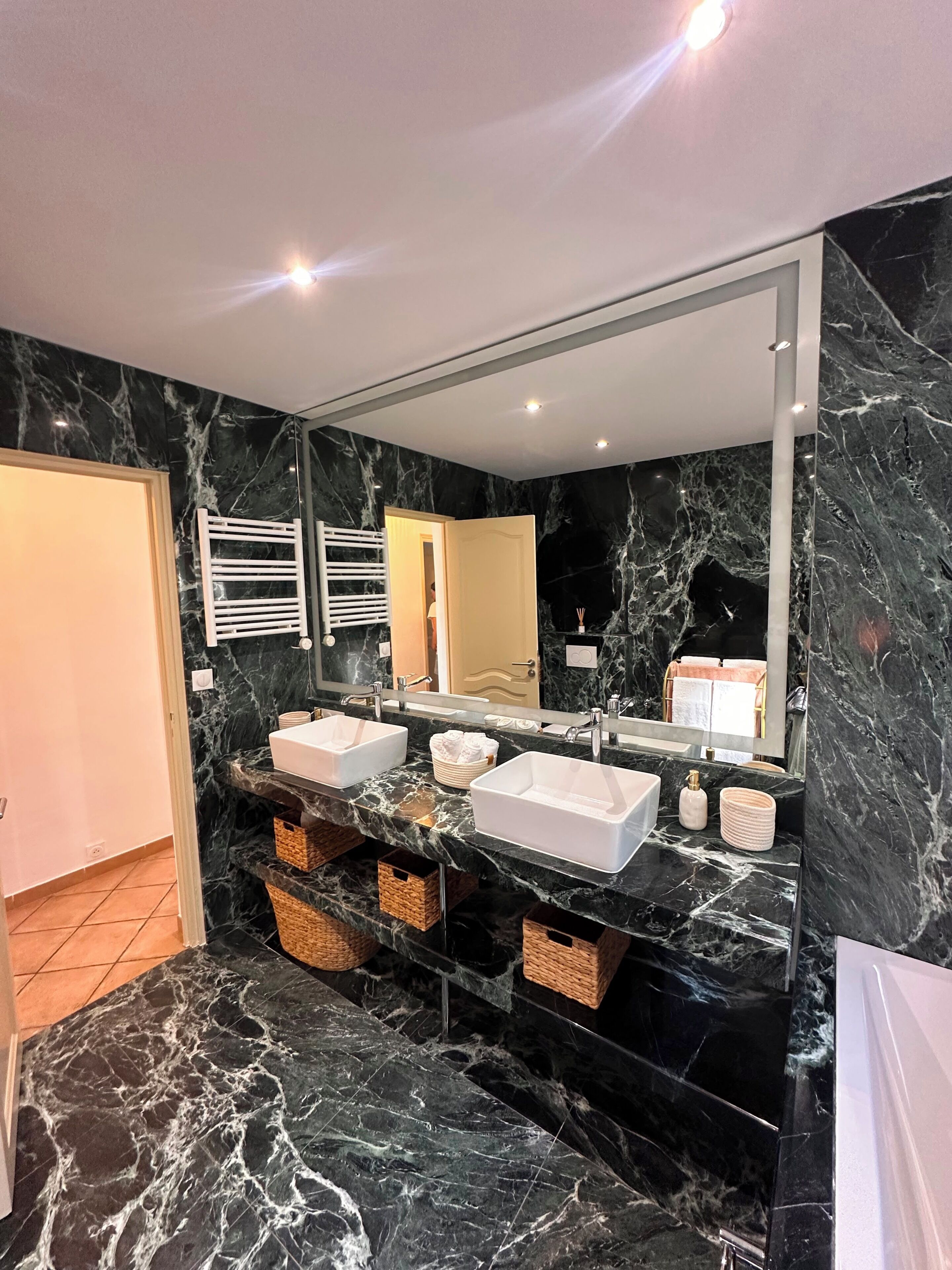 A bathroom with two sinks, a large mirror, and marble flooring.