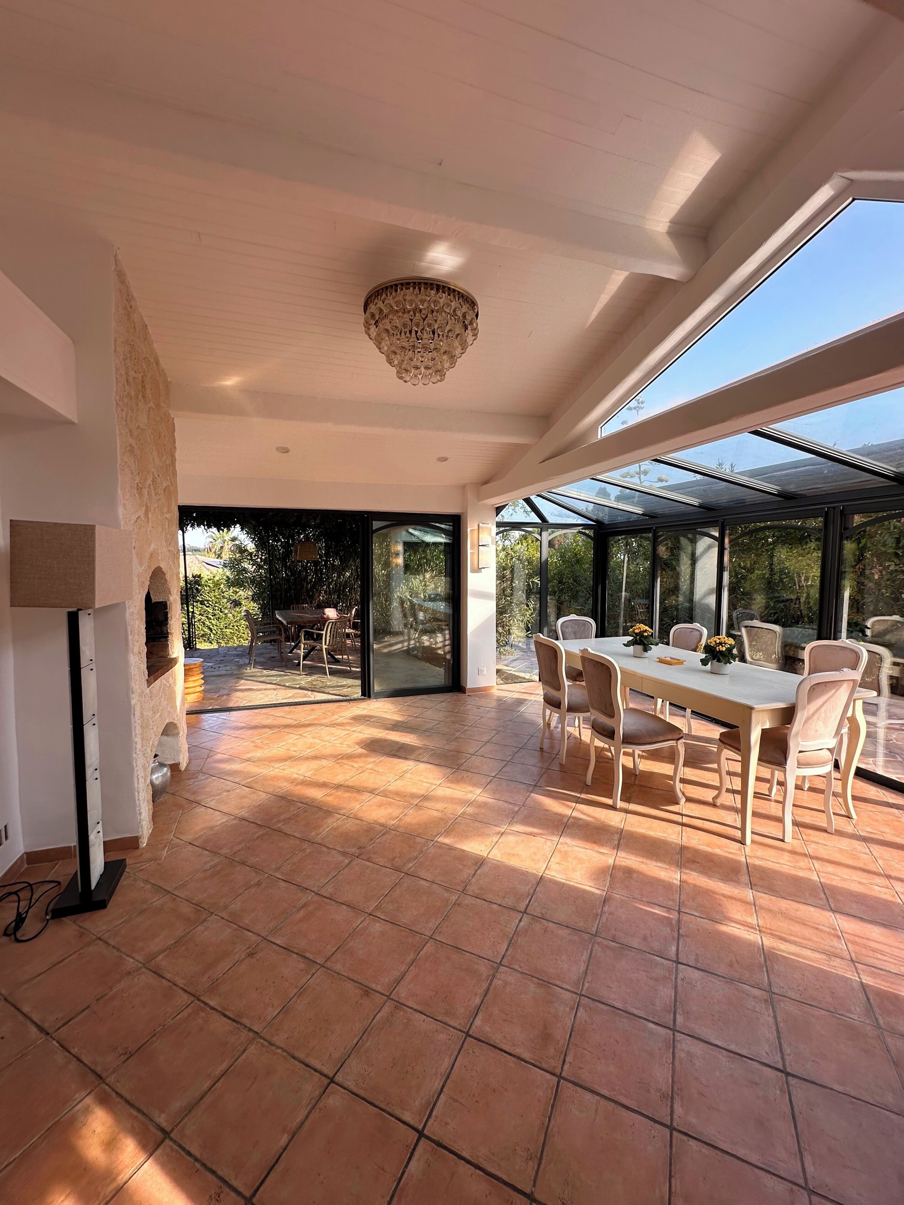 A spacious patio with a dining table and chairs, a stone wall, and a large window providing a view of the outdoors.