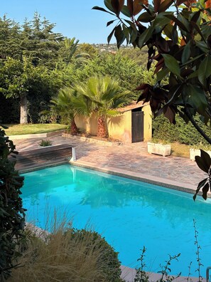 A swimming pool with a stone border, surrounded by greenery and a small building. - Near Saint Tropez Charming 4 bedroom house swimming pool garden  with AC (La Croix-Valmer)