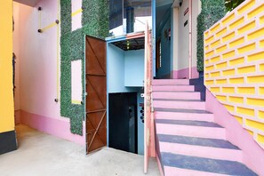 Um edifício com vários andares, uma escadaria, uma área de recepção e uma porta com grade de metal.