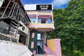 Um hotel com fachada colorida, uma placa indicando serviço YoYo, e uma escadaria que leva à entrada.