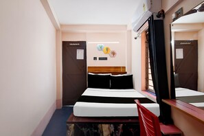 Habitación de hotel con cama, escritorio, silla, espejo y ventana con cortinas.
