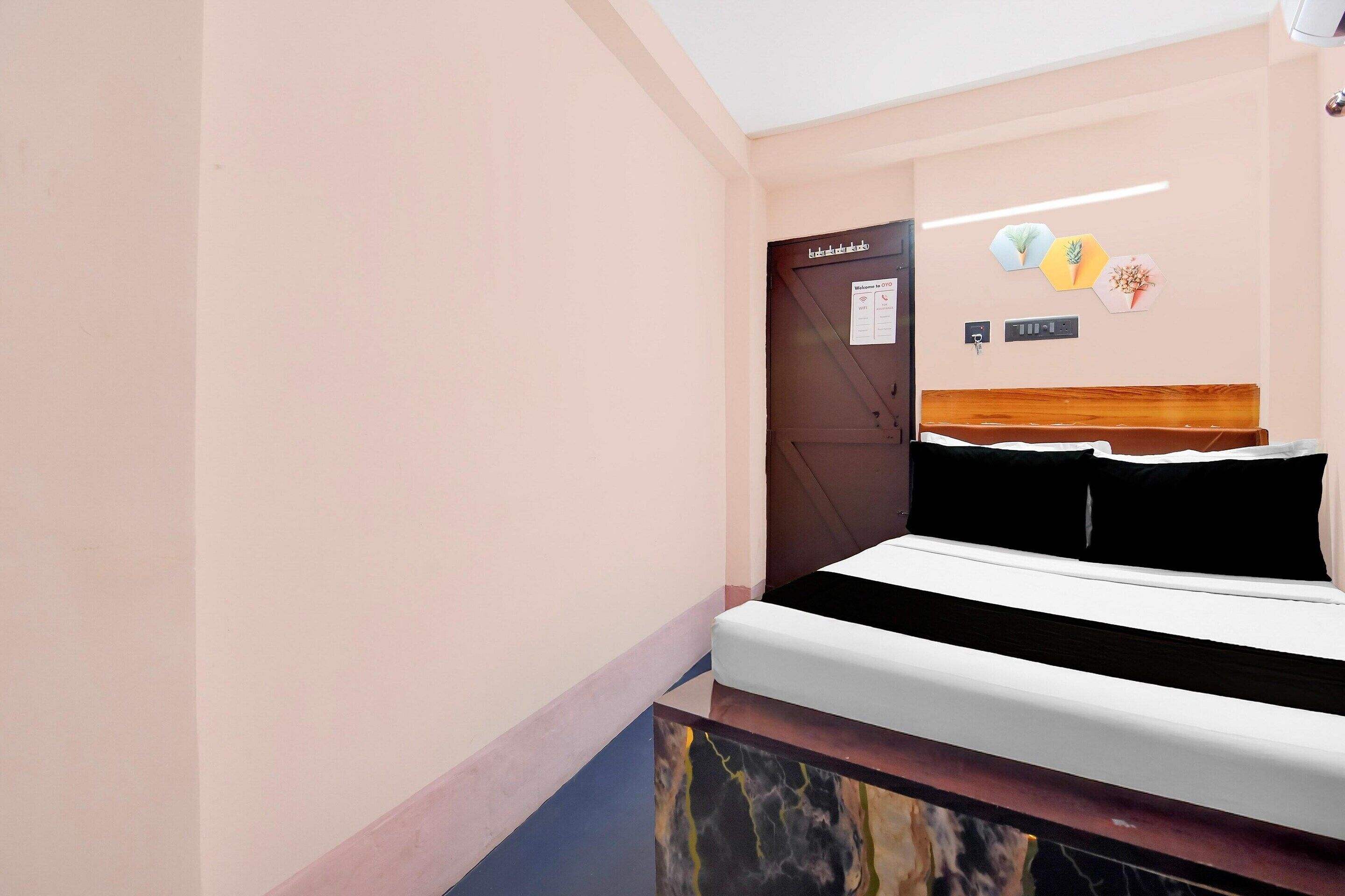 Ein Hotelzimmer mit einem Bett, einer Tür, einem an der Wand befestigten Schild und einer kleinen Wanddekoration.