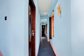 Um corredor com paredes azul-claras, uma porta de madeira e uma janela com cortinas.