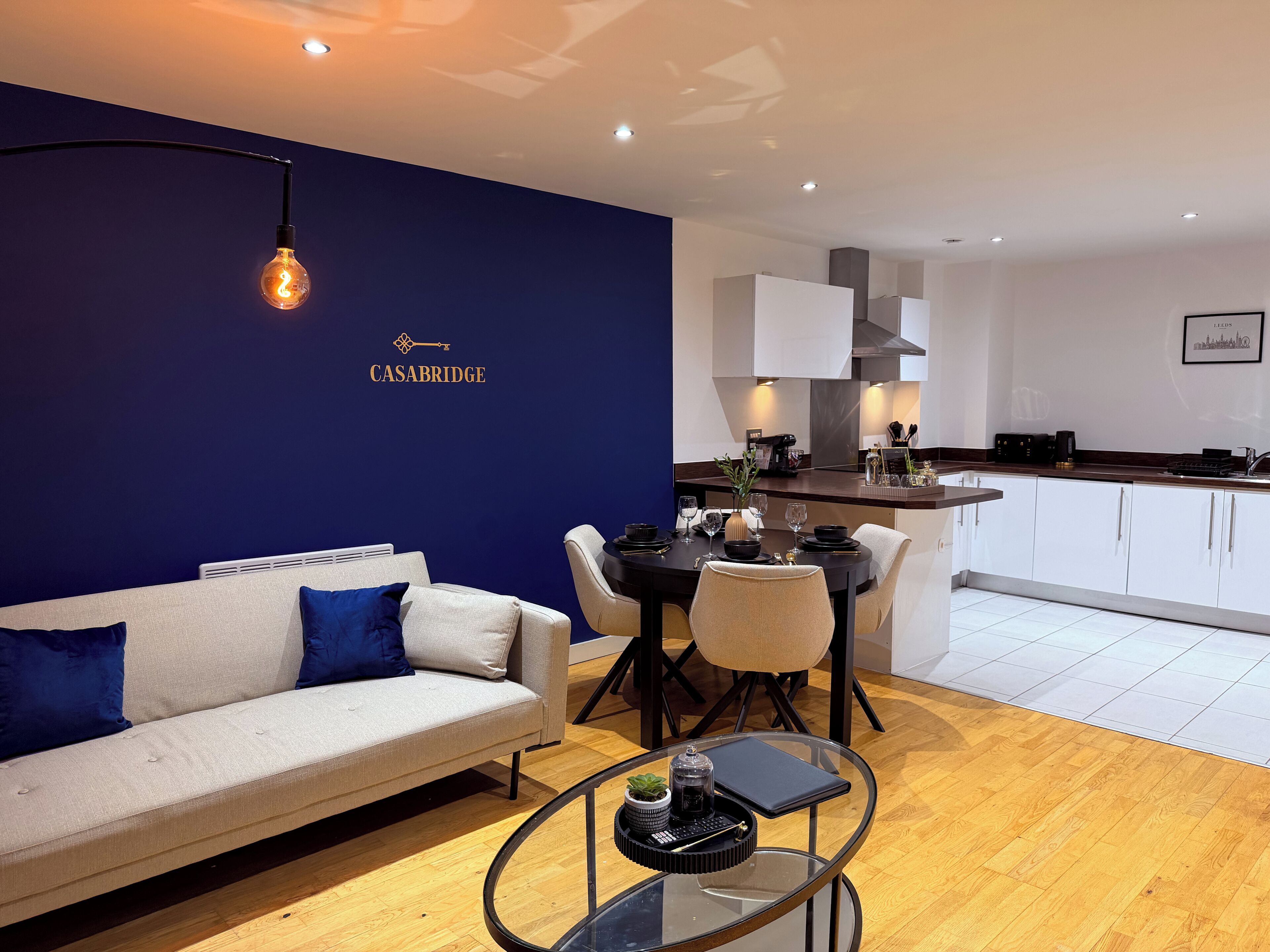 A modern living room with a sofa, coffee table, and a dining area with chairs and a table.
