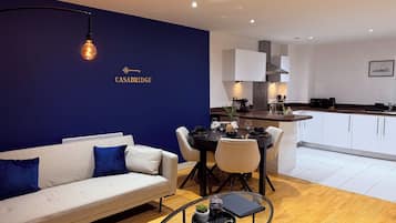 A modern living room with a sofa, coffee table, and a dining area with chairs and a table.
