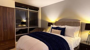 A bedroom with a bed, bedside tables, a wardrobe, and a window.