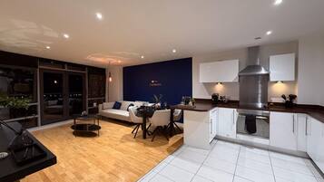 A modern living space with a dining area, a kitchen, and a sofa.