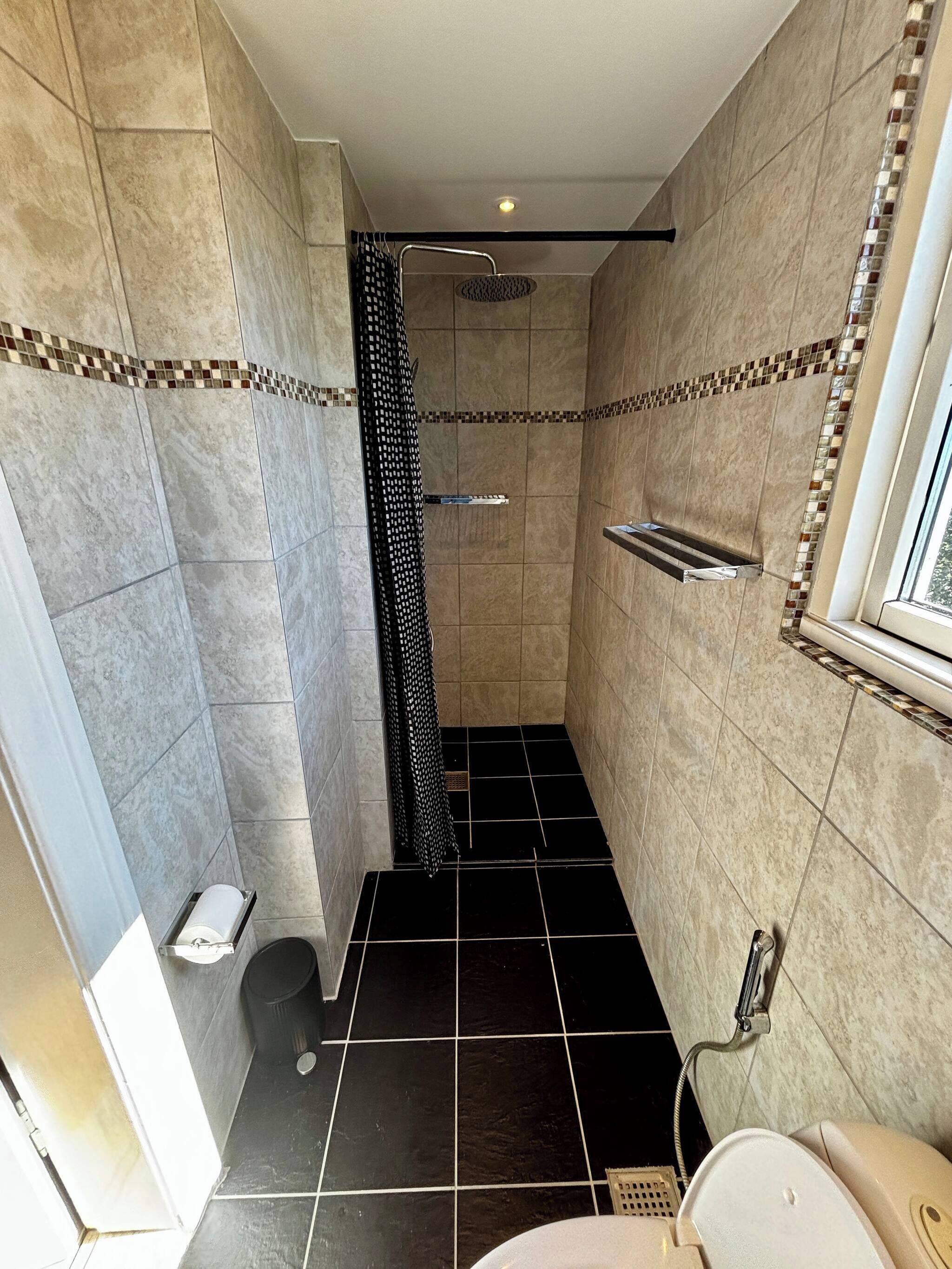 A bathroom with a shower, a toilet, and a sink.