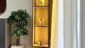 Ein Flur mit einem hohen, beleuchteten Regal, das Blumenarrangements zeigt.