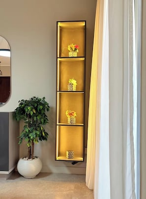 Ein Flur mit einem hohen, beleuchteten Regal, das Blumenarrangements zeigt.