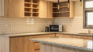 Eine moderne Küche mit Holdekor, einer Granit-Arbeitsplatte und Pendelleuchten.