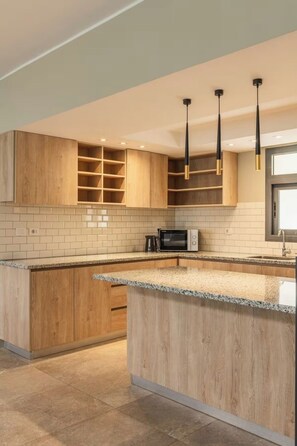 Eine moderne Küche mit Holdekor, einer Granit-Arbeitsplatte und Pendelleuchten.