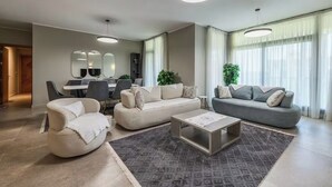 Ein modernes Wohnzimmer mit einer Sofagarnitur, einem Couchtisch und einem Essbereich mit Stühlen und Tisch.