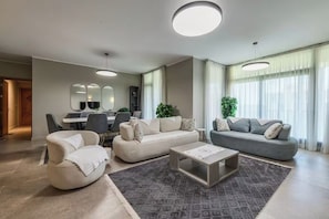 Ein modernes Wohnzimmer mit einer Sofagarnitur, einem Couchtisch und einem Essbereich mit Stühlen und Tisch.