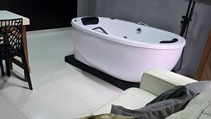 A modern bathroom with a freestanding bathtub, a chair, and a sofa.