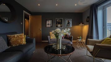 Un salon moderne avec un canapé, un fauteuil, une table basse et des œuvres d’art accrochées au mur.