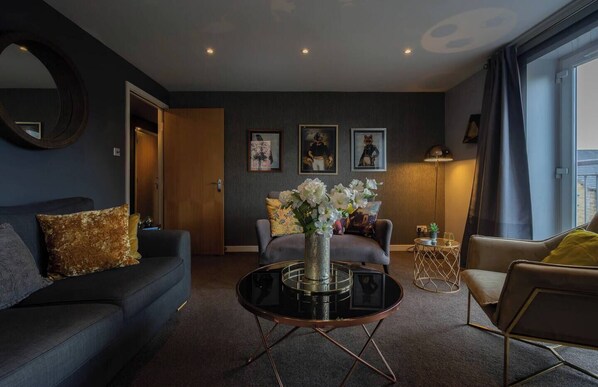 Un salon moderne avec un canapé, un fauteuil, une table basse et des œuvres d’art accrochées au mur.