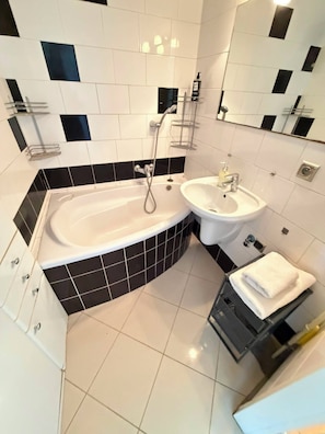 A modern bathroom with a bathtub, a sink, and a towel rack. - Warsaw Core 3-bedrooms apartment in City Center, Pet Friendly (Warszawa)