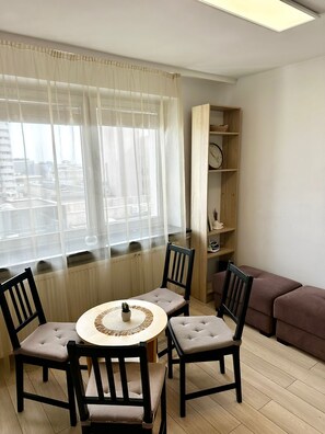 A room with a dining table and chairs, a bookshelf, a clock, and a sofa. - Warsaw Core 3-bedrooms apartment in City Center, Pet Friendly (Warszawa)