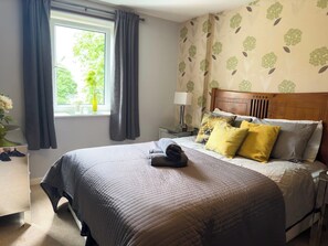 A hotel room with a bed, a nightstand, a lamp, and a window with curtains. - Our apartment is close to the City Centre and Leith (Edinburgh)