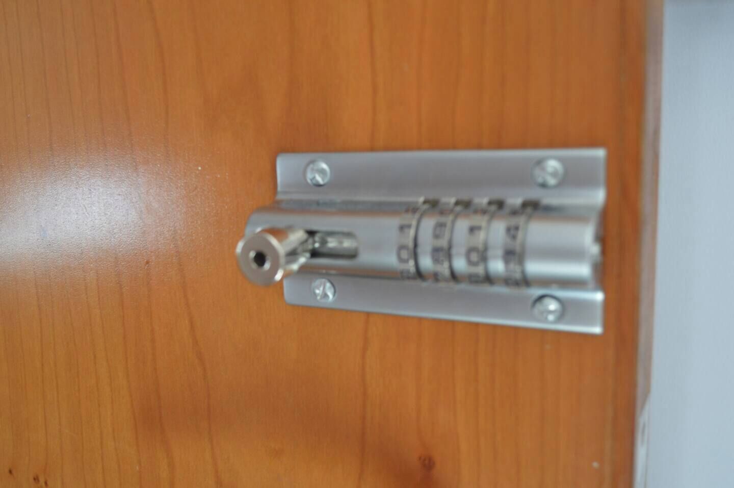 A metallic door latch on a wooden door.