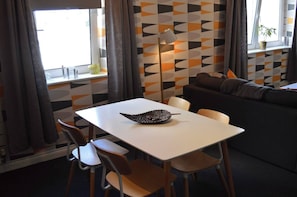 A dining area with a white table, chairs, and a decorative bowl. There is a sofa and a floor lamp in the background. - Our apartment is close to the City Centre and Leith (Edinburgh)