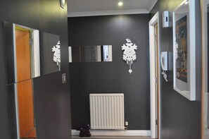 A hallway with a radiator, a door, and a coat rack. - Our apartment is close to the City Centre and Leith (Edinburgh)