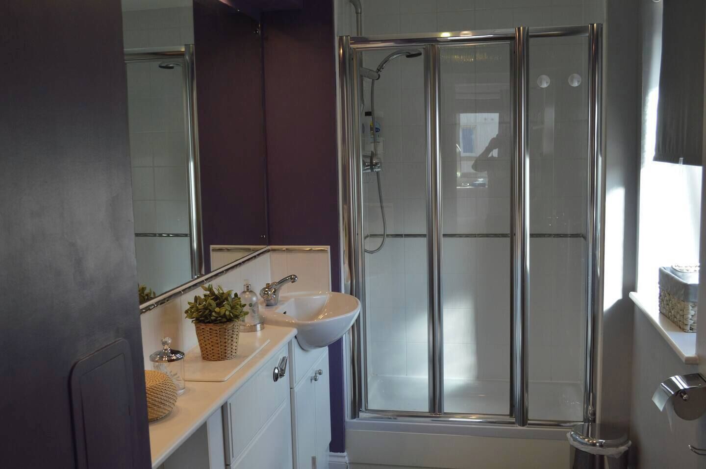 Une salle de bain avec une douche à parois de verre, un lavabo et un miroir.
