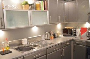 A modern kitchen with stainless steel appliances, including a microwave and a kettle, and a built-in sink. - Our apartment is close to the City Centre and Leith (Edinburgh)