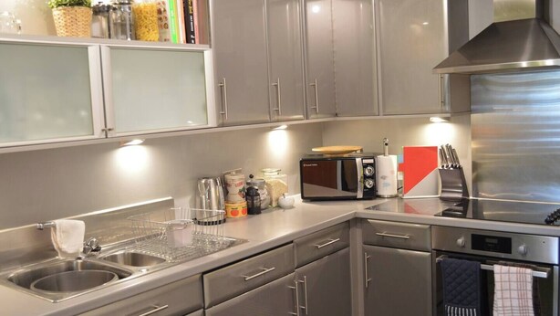 Eine moderne Küche mit Edelstahlgeräten, darunter eine Mikrowelle, ein Backofen und ein Spülbecken.