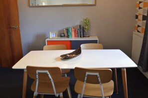 A conference room with a white table, two chairs, a bookshelf with books, a framed picture, and a potted plant. - Our apartment is close to the City Centre and Leith (Edinburgh)