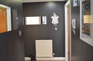 Um corredor com um radiador, um objeto decorativo na parede e um quadro emoldurado.