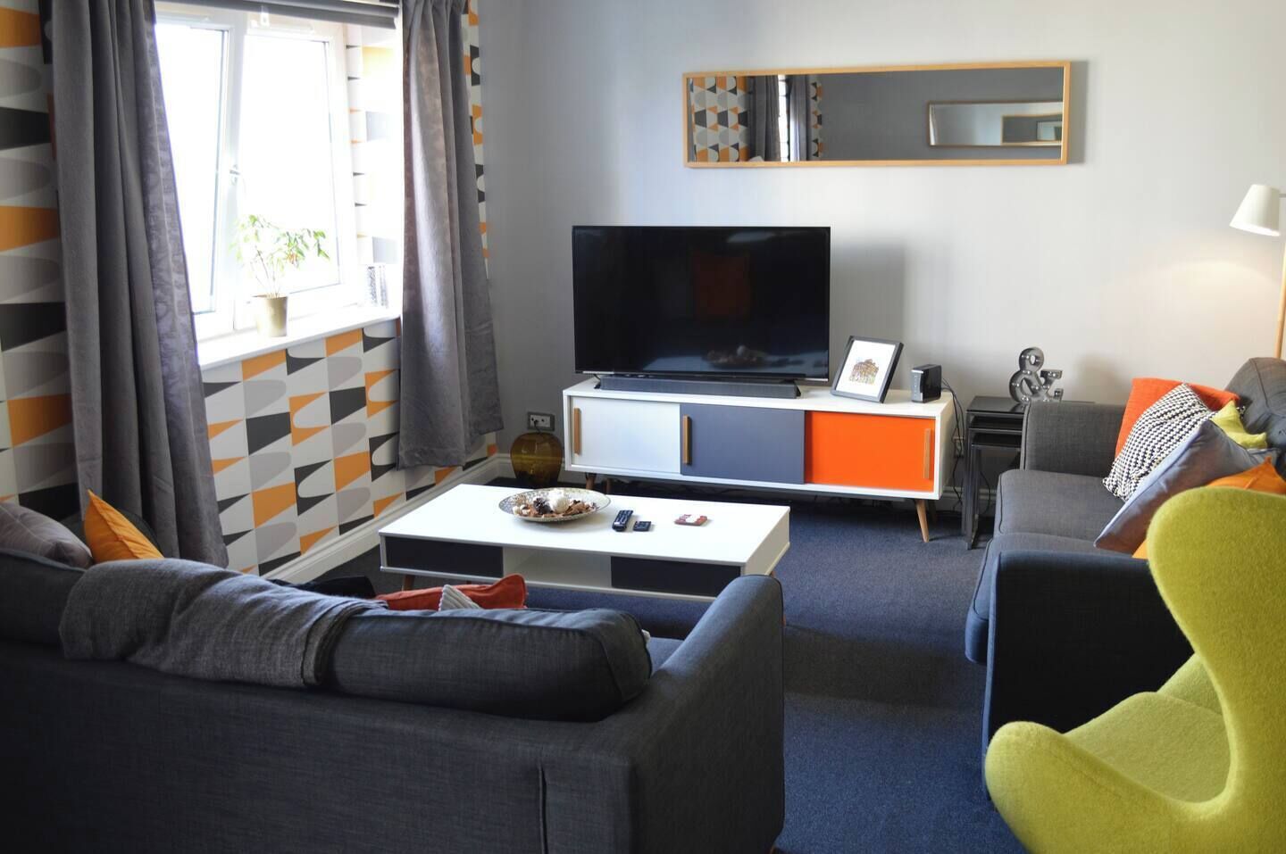 A modern living room with a sofa, a coffee table, a television, and a cabinet.