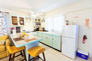 Eine kleine Küche mit einer zentralen Kochinsel, einem Kühlschrank und einer Mikrowelle.