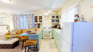 A compact kitchen with a dining area, a sofa, and a coffee table. - Island Studio with Pool Access, Porch & Workspace (Venetian Road Settlement)