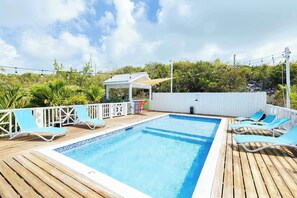 A pool area with a wooden deck, lounge chairs, and a covered seating area. - Island Studio with Pool Access, Porch & Workspace (Venetian Road Settlement)