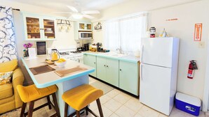 A compact kitchen with a central island, a refrigerator, and a microwave. - Island Studio with Pool Access, Porch & Workspace (Venetian Road Settlement)