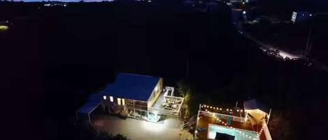 A property with a main building, a swimming pool, and a covered outdoor area.