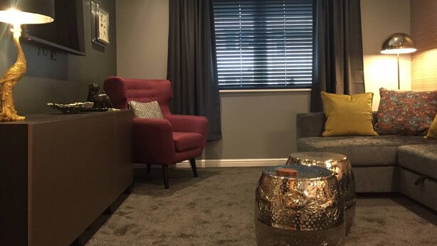 A living room with a red armchair, a grey sofa with yellow cushions, a coffee table, and a window with blinds. - Boutique apartment newly decorated (Edinburgh)