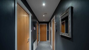 A hallway with wooden doors, a radiator, and a mirror on the wall. - Boutique apartment newly decorated (Edinburgh)