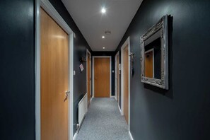 Ein Flur mit Holztüren, einem Heizkörper und einem Spiegel an der Wand.