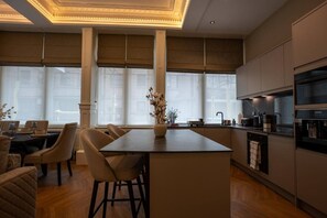A modern kitchen with a central island, bar stools, and a dining area with a table and chairs. - Grand Leith Luxe: Jacuzzi & Cinema Room (Edinburgh)