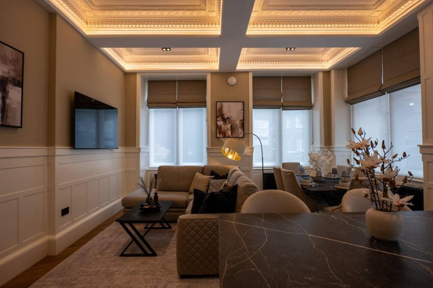 A modern living room with a sofa, coffee table, and dining table.
